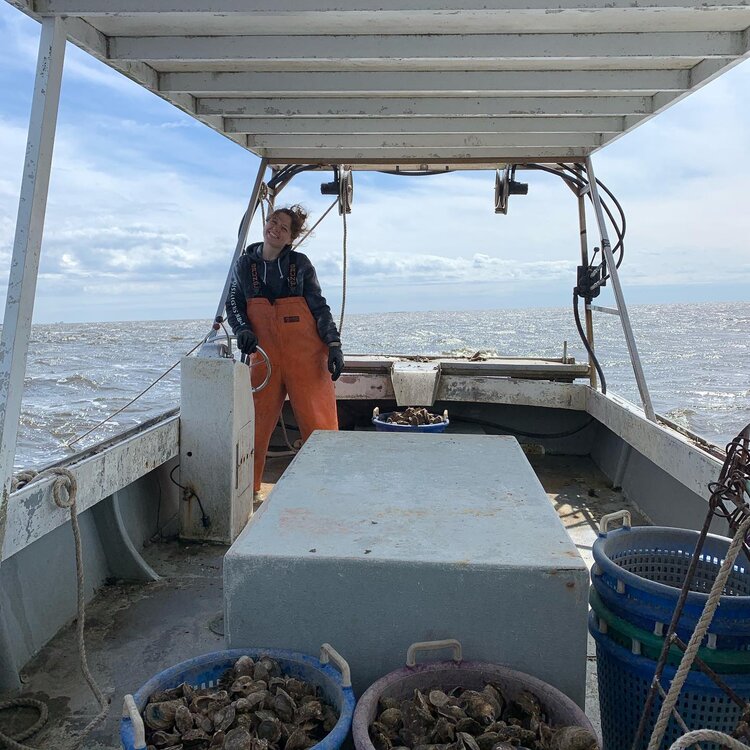 Gretchen Maxwell smiling, on a boat harvesting oysters