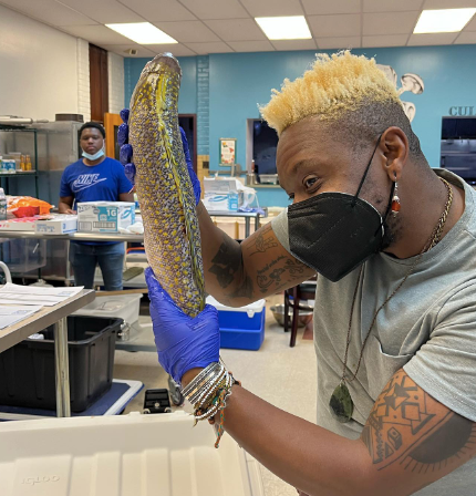 Omi Masika holds up a tilefish during a fish packing session at Gratz