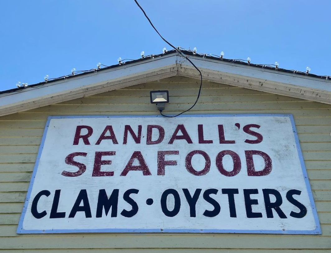 The handpainted sign at Randall's Seafood. It says the name of the store, and also "clams; oysters".