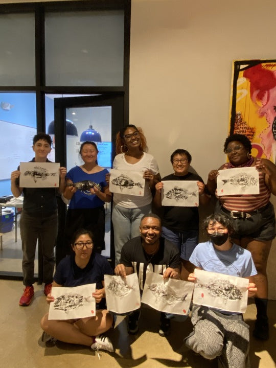 Fishadelphia staff smiling and holding gyotaku fish prints from the Fishadelphia summer 2024 staff retreat