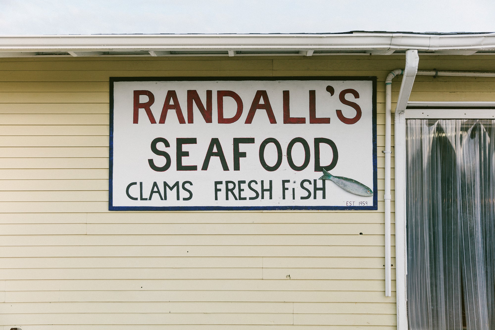 The handpainted sign at Randall's Seafood. It says the name of the store, and also "clams; fresh fish".